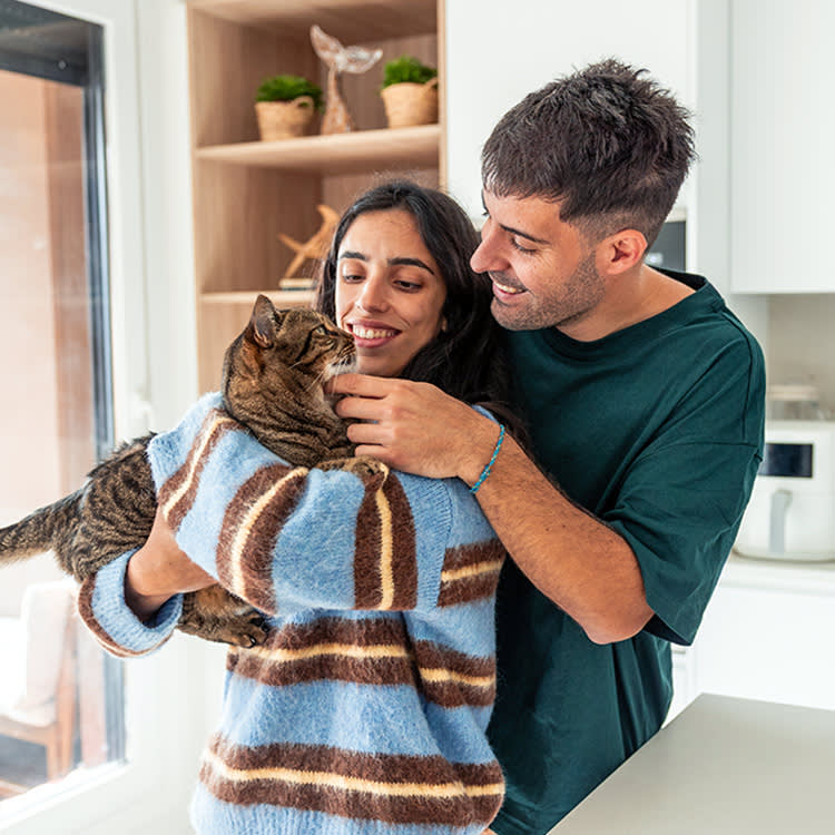 Couple holding their cat at home.