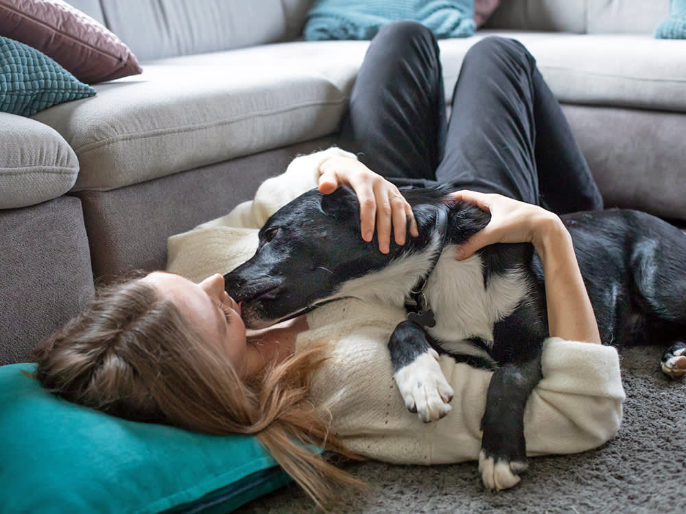 Woman cuddling her dog on the floor.