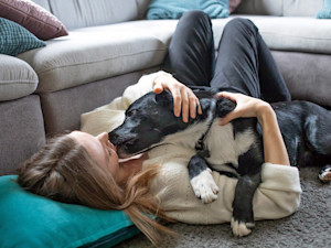 Woman cuddling her dog on the floor.