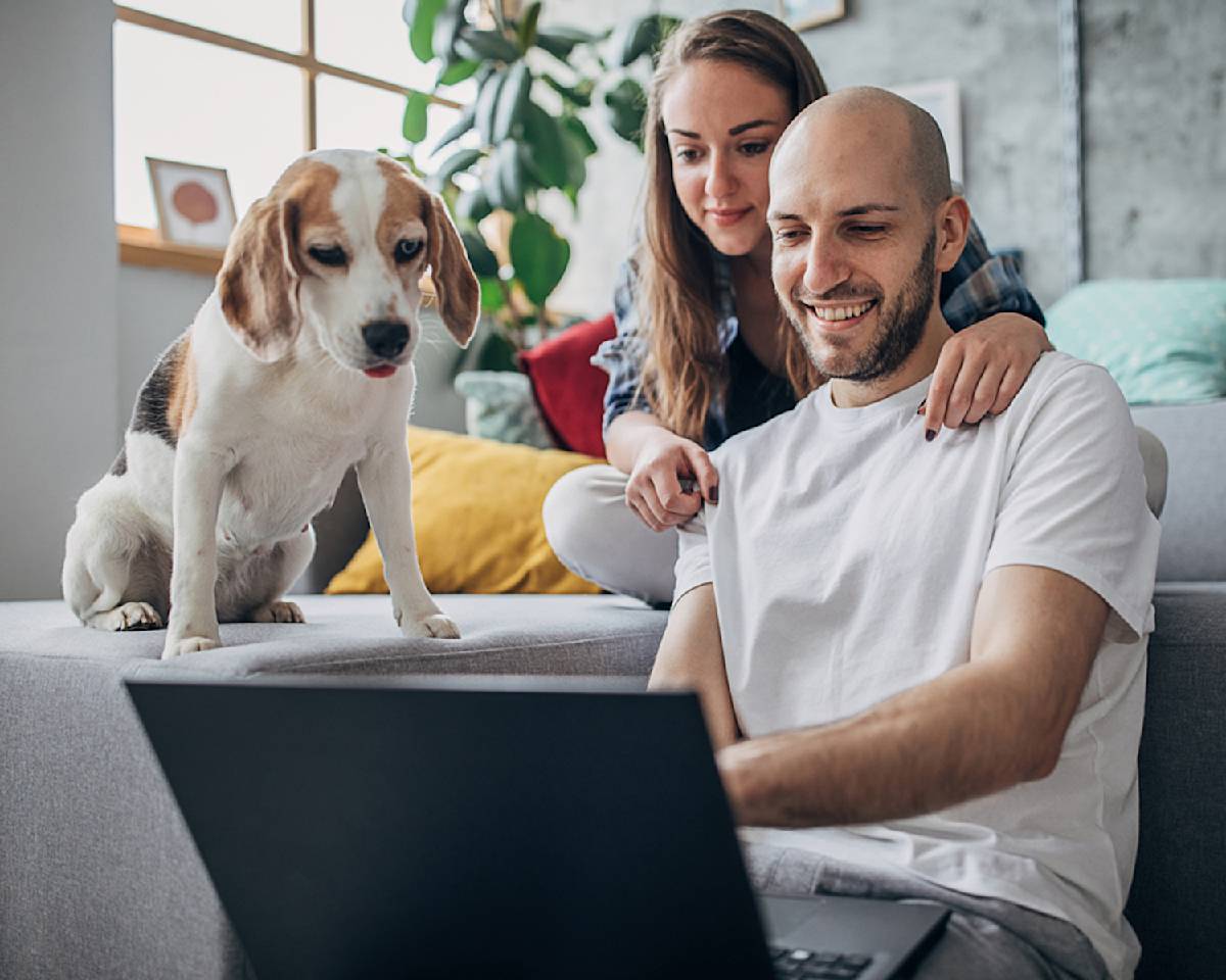 two people and a beagle look at a laptop