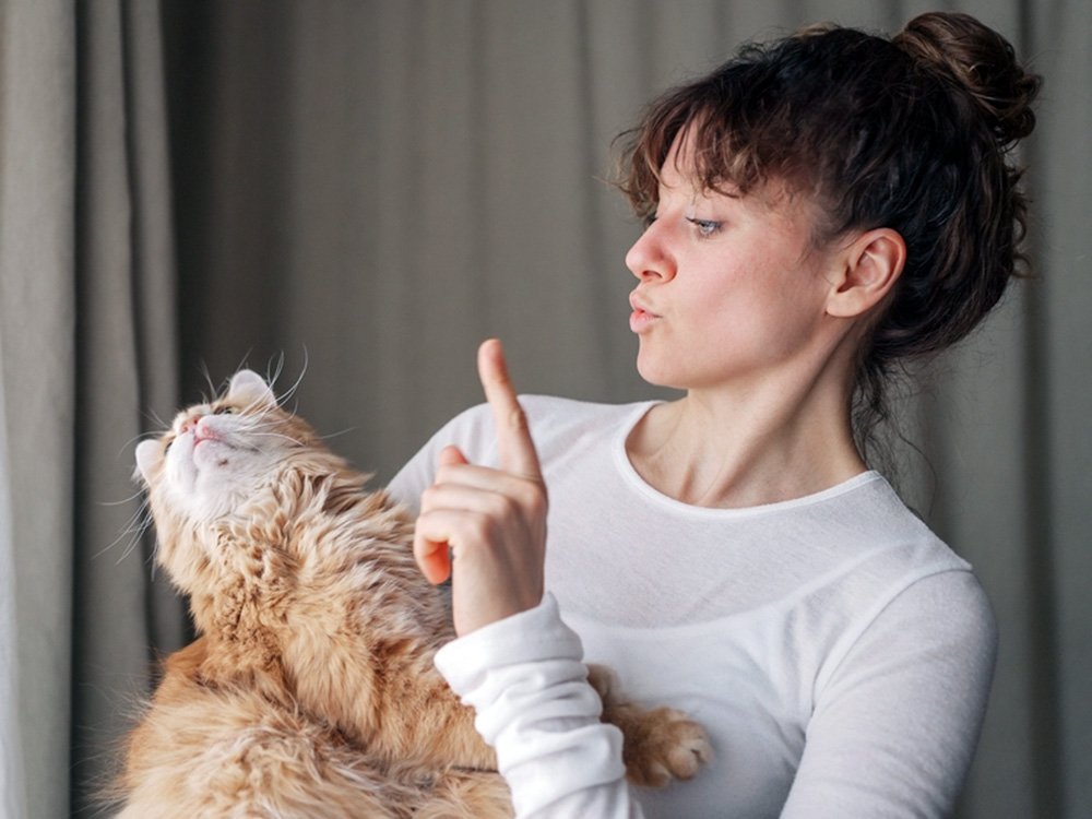 Woman holding her orange cat in her arms.