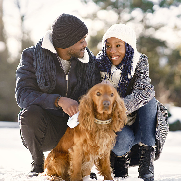 Couple outside with their dog in the snow.