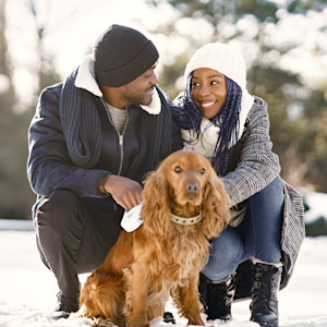 Couple outside with their dog in the snow.