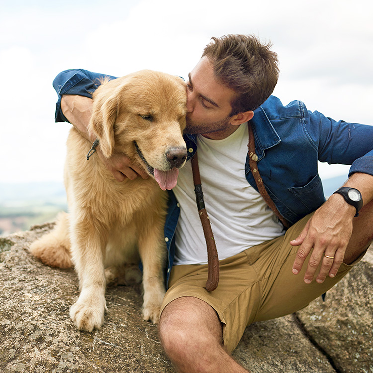Man cuddling his dog outside.