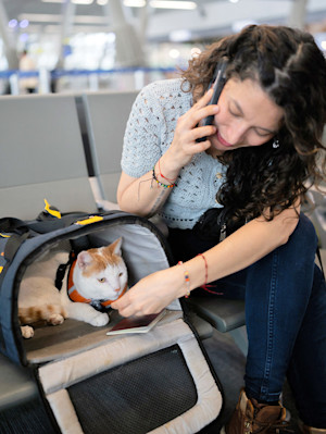 Woman with her cat in a carrier at the airport.