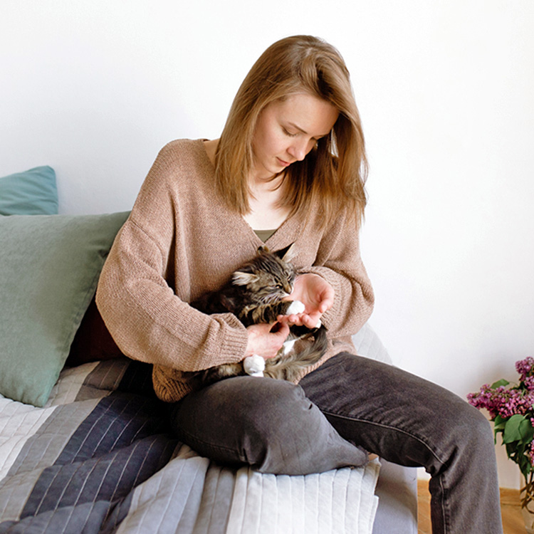 Woman comforting her kitten in her lap.