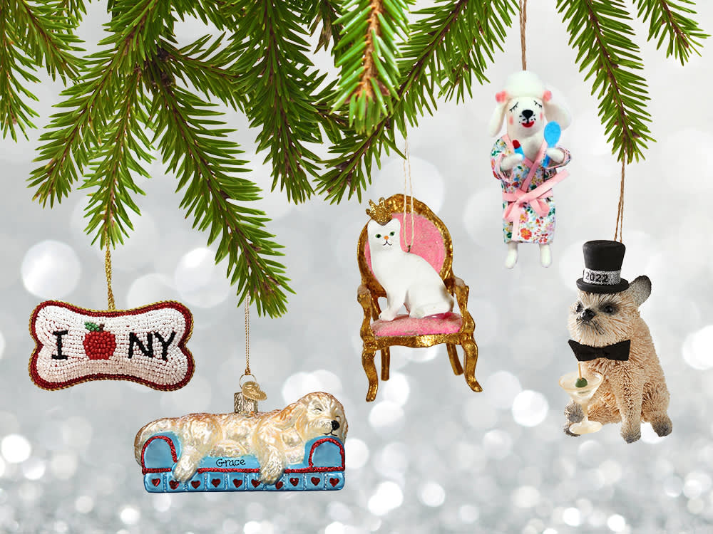 Five fun holiday ornaments of pets in various costumes hanging from Christmas tree boughs against a sparkly silver background