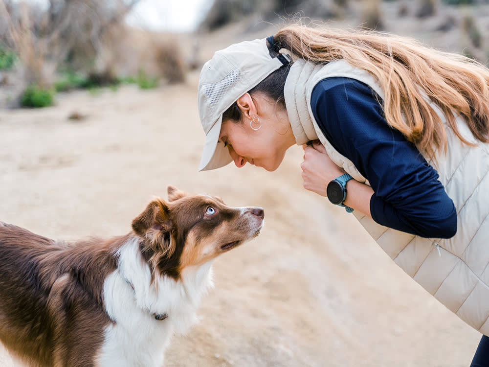 Woman looking into her dog's eyes while outside.