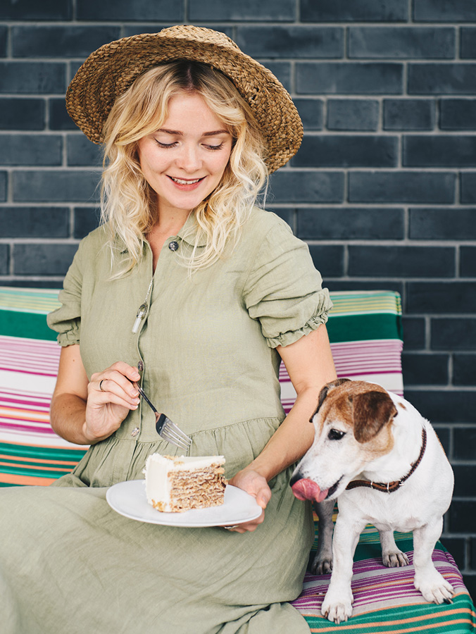 Woman and her dog sharing a piece of cake.