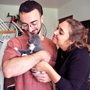 Man and woman cuddling their kitten at home.