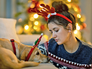 Woman comforting her dog at home during the holidays.