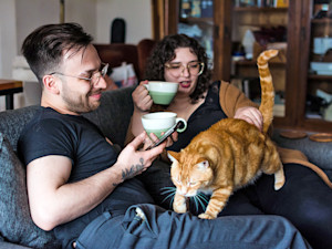 Funny orange cat walking over people's legs at home.