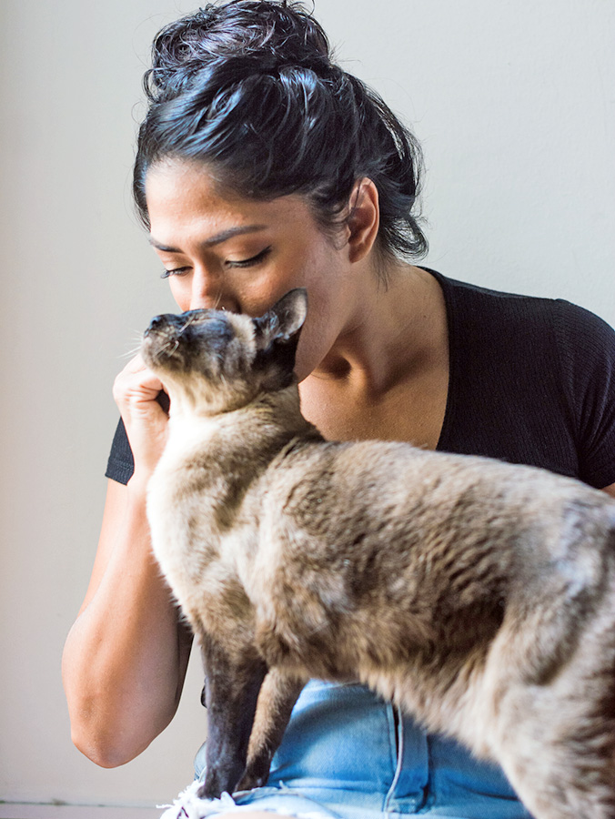 Woman kissing her pet cat at home.