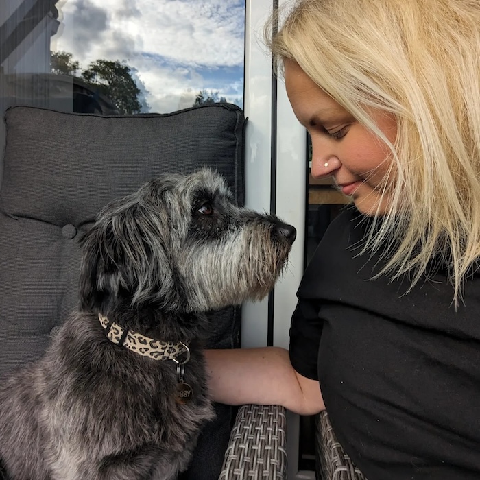 a blonde woman looks into a grey dog's eyes