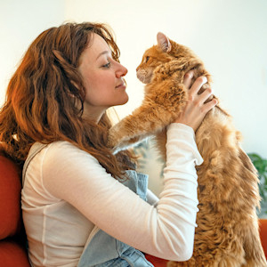 Woman holding her cat in the air.