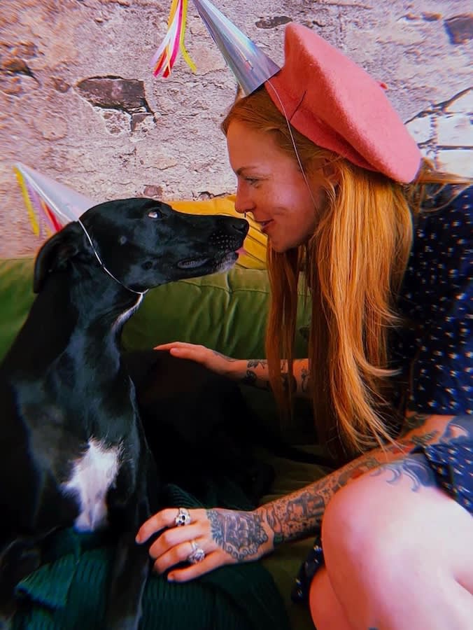 a girl and a dog wearing birthday hats put their noses together