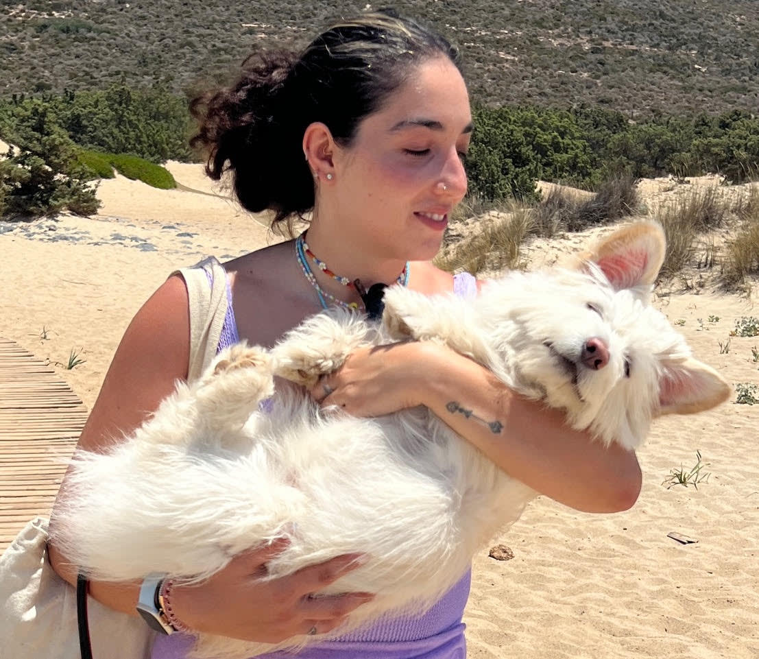 a woman with black hair hugs her white fluffy dog