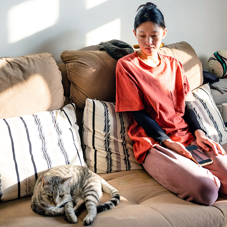Woman looking at her cat sadly at home.