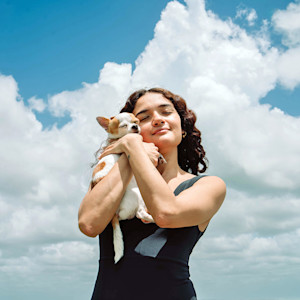 Woman holding her small Chihuahua in her arms outside.