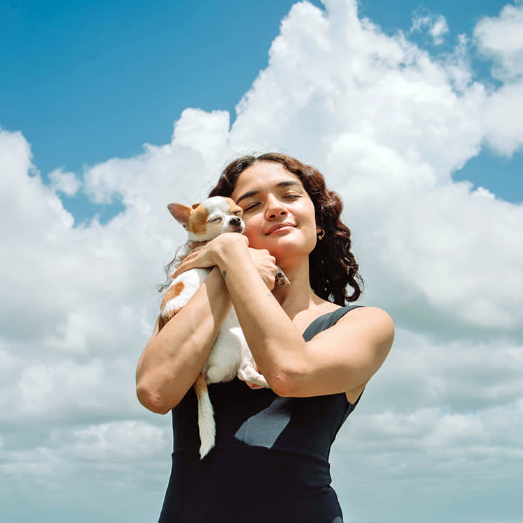 Woman holding her small Chihuahua in her arms outside.