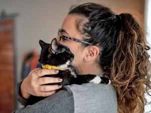 Woman snuggling her cat at home.