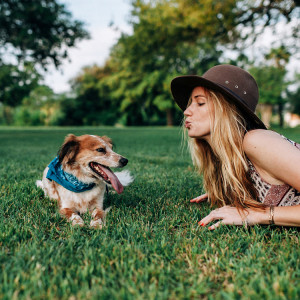 A woman playing with her dog making a kiss face at it.