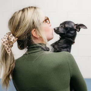 A woman making a kiss face next to a dog. 