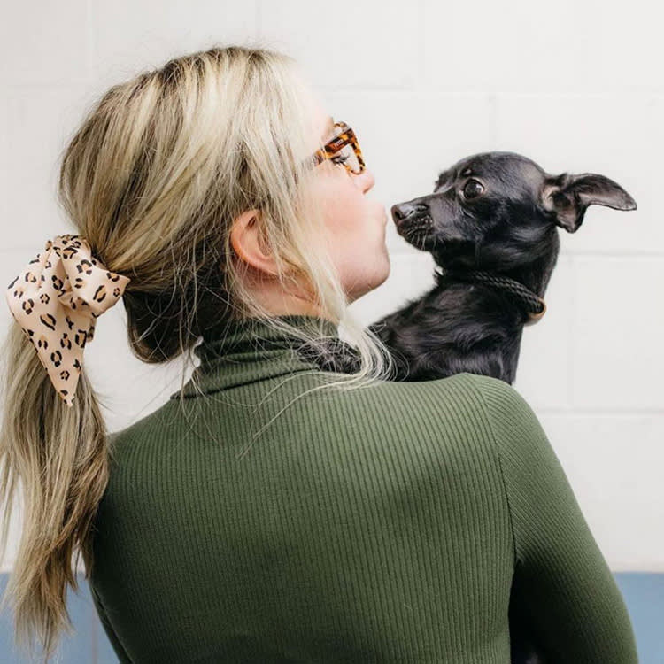 A woman making a kiss face next to a dog. 