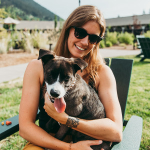 A woman petting her dog on a a chair at Outbound Hotel