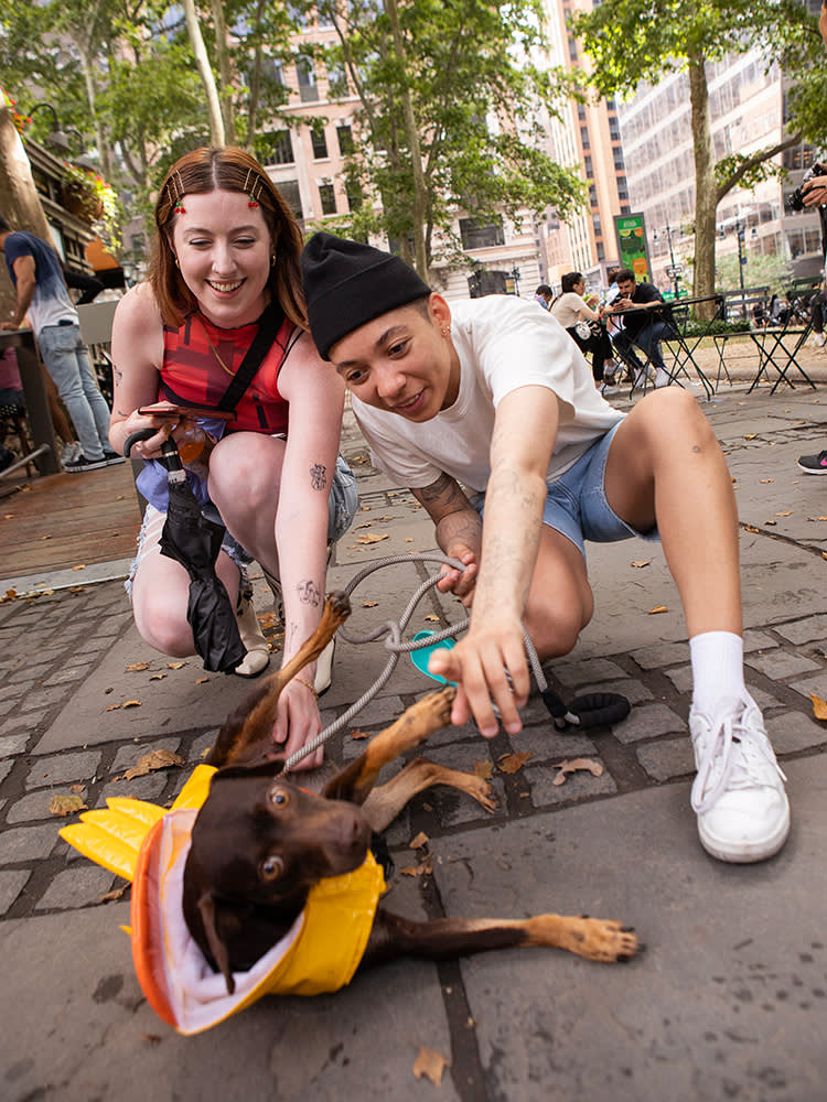 Melanie (left) and Kayla pose with their dog, Navy, who wears a yellow raincoat