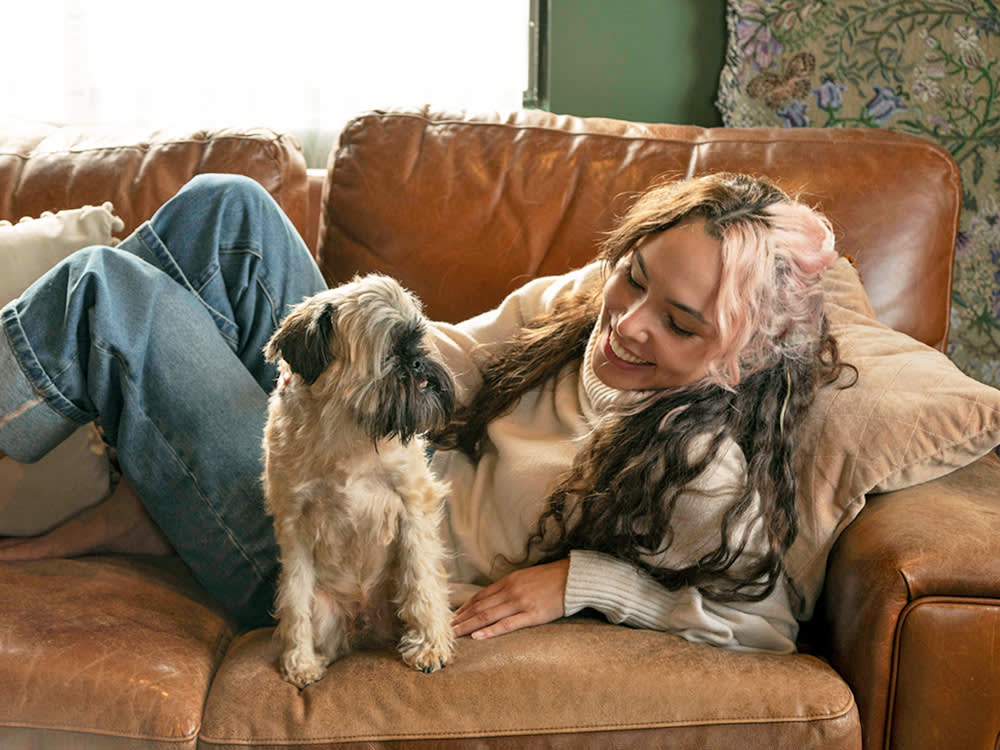 Woman laying with her dog on the couch at home.