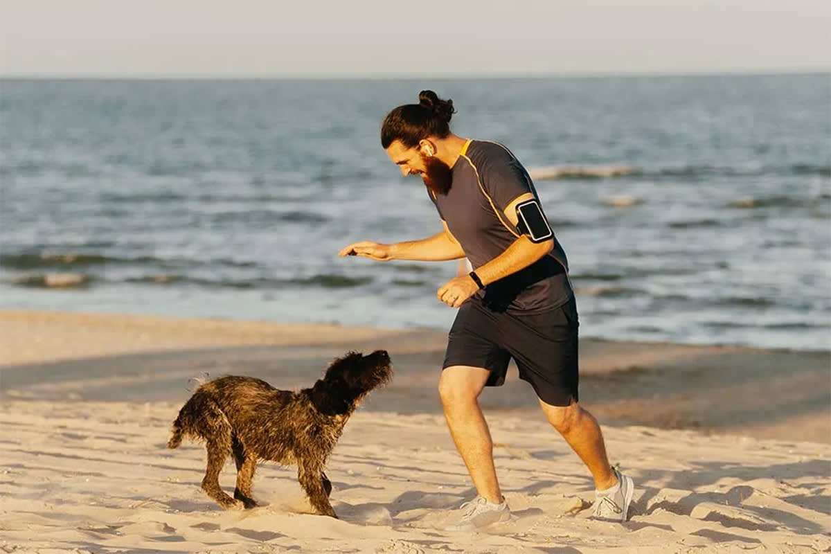 man playing with his dog at the beach
