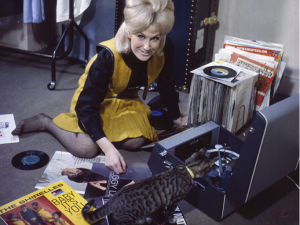 Dusty Springfield sitting on the floor with a record player and a cat 