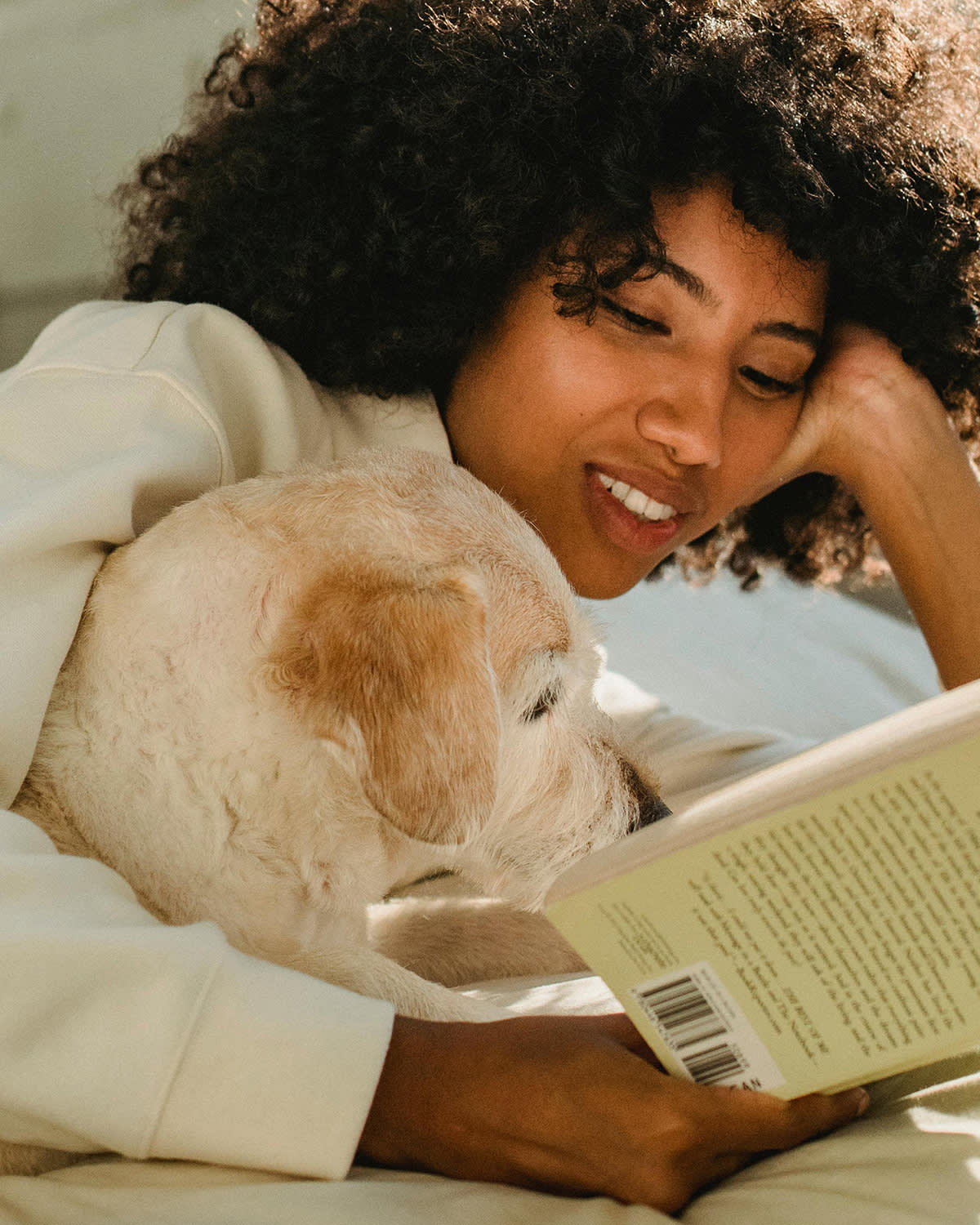 woman and dog lying in bed reading a book