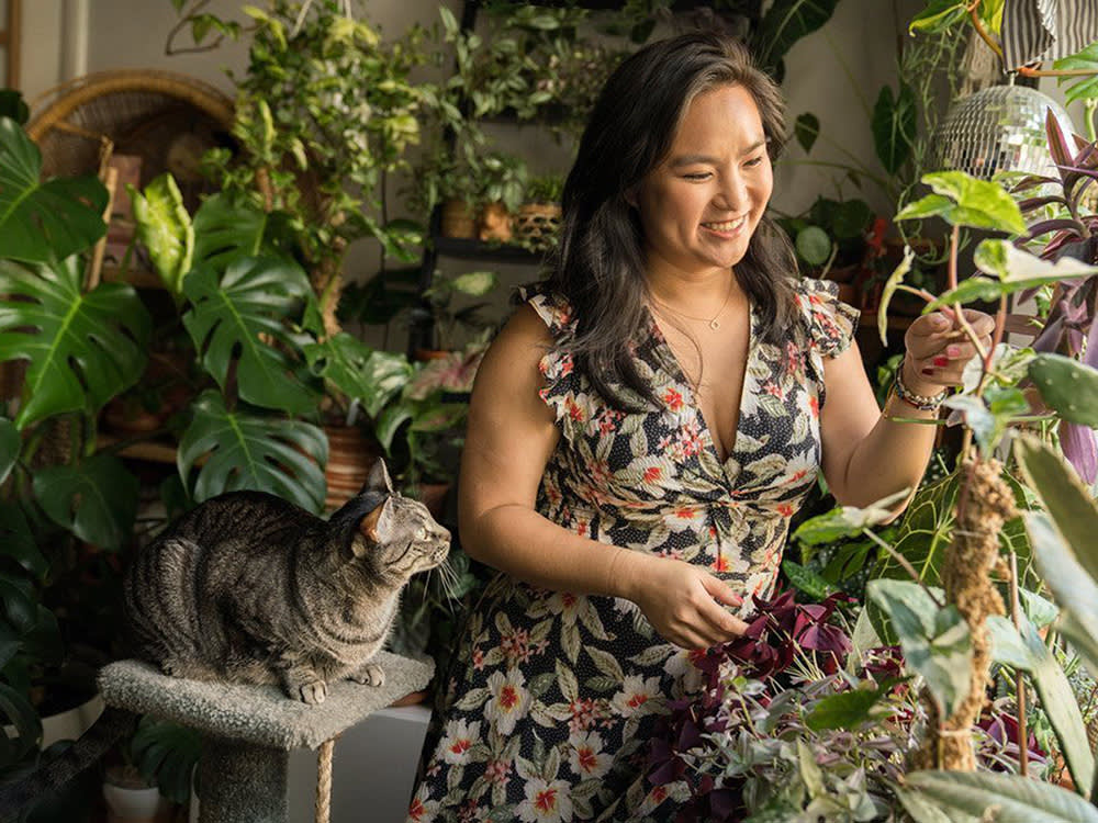 Phoebe Cheong in her home with her cat, surrounded by plants