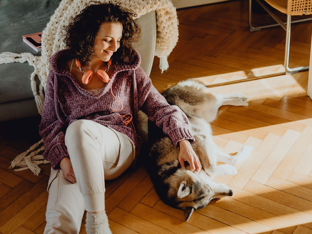 woman and dog sit on pet-friendly wood flooring in a chevron pattern