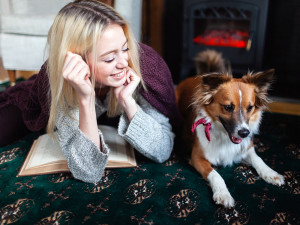 Woman Playing With Her Dog While Reading.
