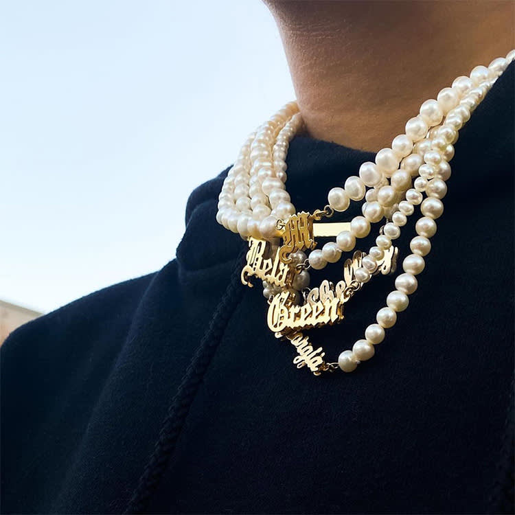 A photograph of a person wearing layered pearl necklaces. 