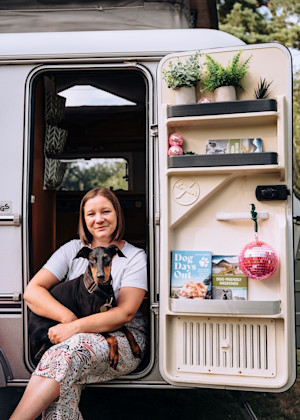 a woman and her dog sit in a camper van door