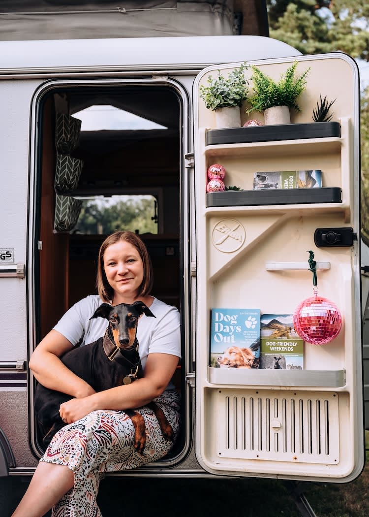 a woman and her dog sit in a camper van door