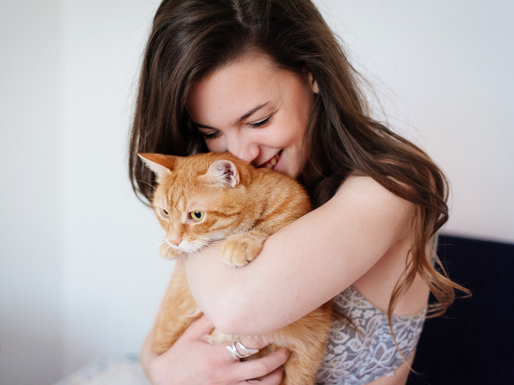 Woman hugging her orange cat at home.