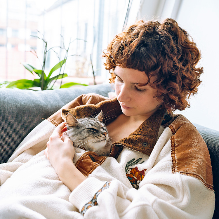 Woman snuggling with sleeping cat.