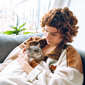 Woman snuggling with sleeping cat.