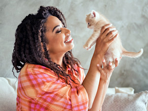 Woman holding small kitten in her hands.