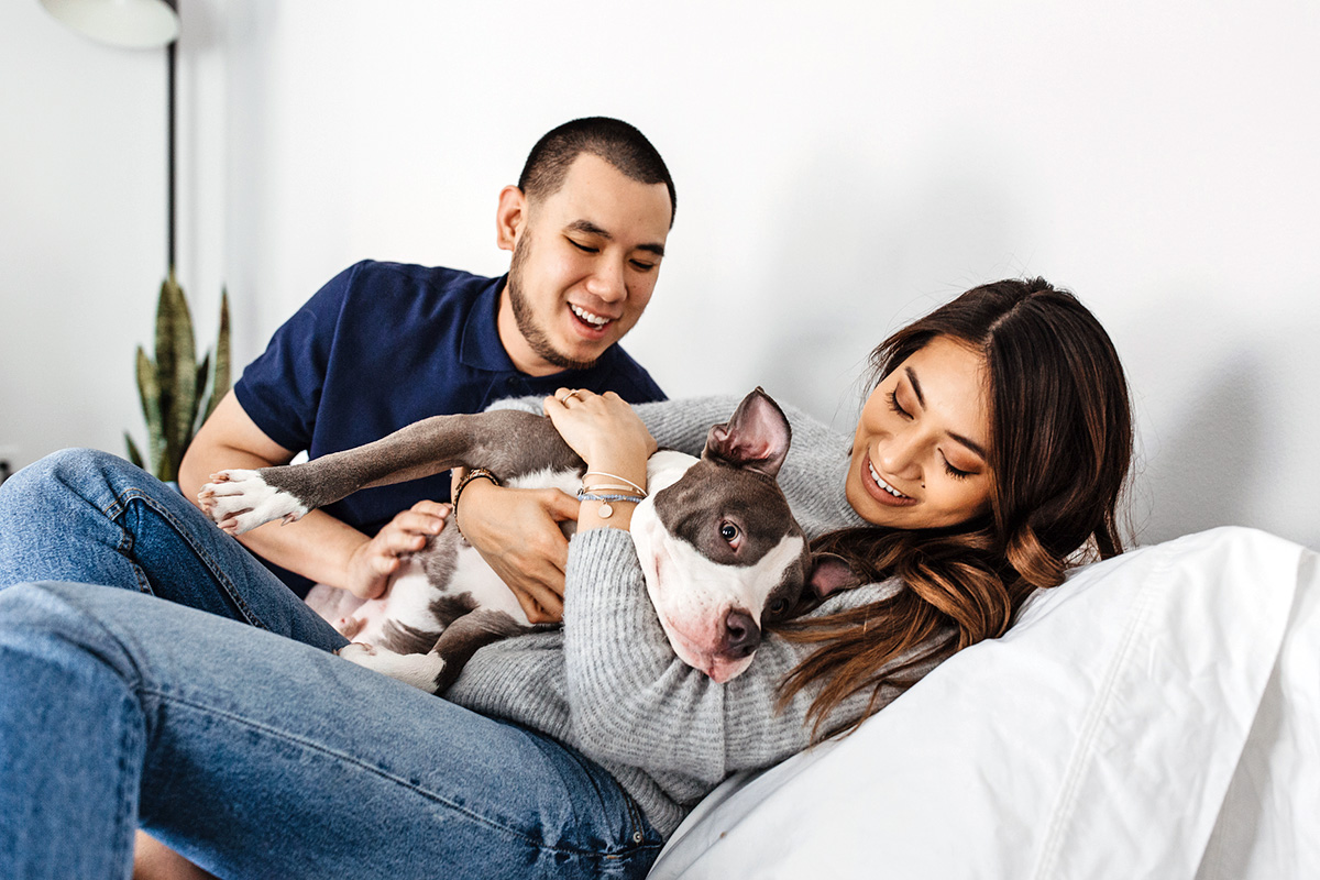two people cuddling with a black and white dog