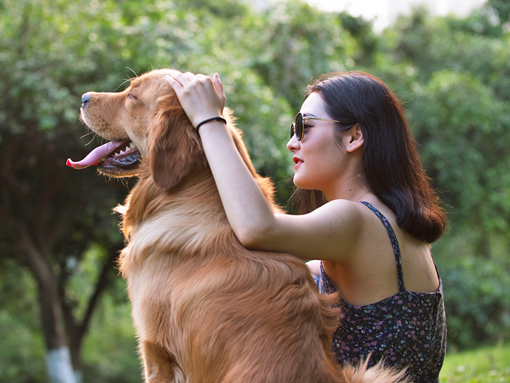 Woman petting her dog outside at the park.