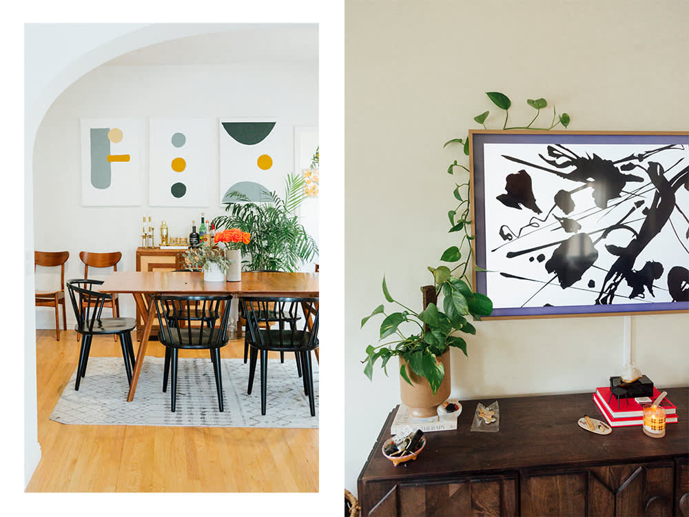 a dining room table with abstract circle and line art on the wall; a mirror and a plant