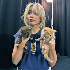 Sabrina Carpenter holding up two kittens.