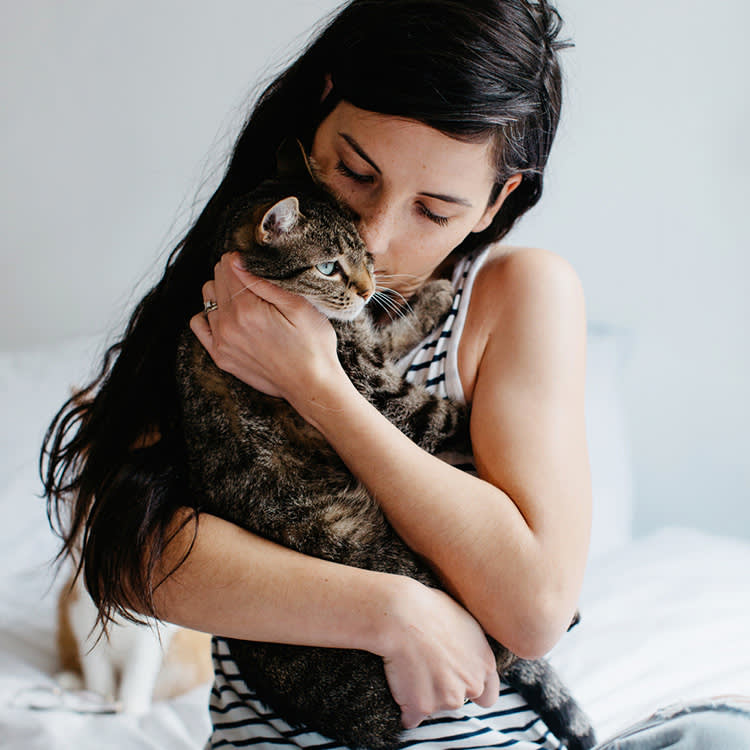 dark-haired woman hugging cat that has imprinted on her