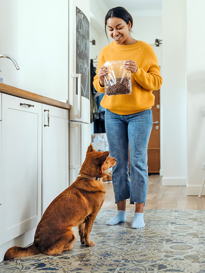 Woman feeding her dog at home.